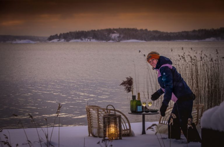 Magdalena dukar upp en bord med mousserande dryck på stranden mitt i vintern.