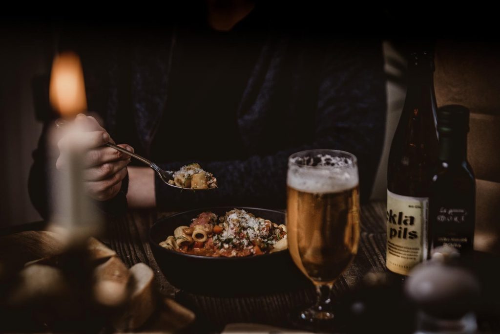 Närbild på middag på Almåsa. En tallrik med mat, ett glas öl och i förgrunden ett tänt ljus.